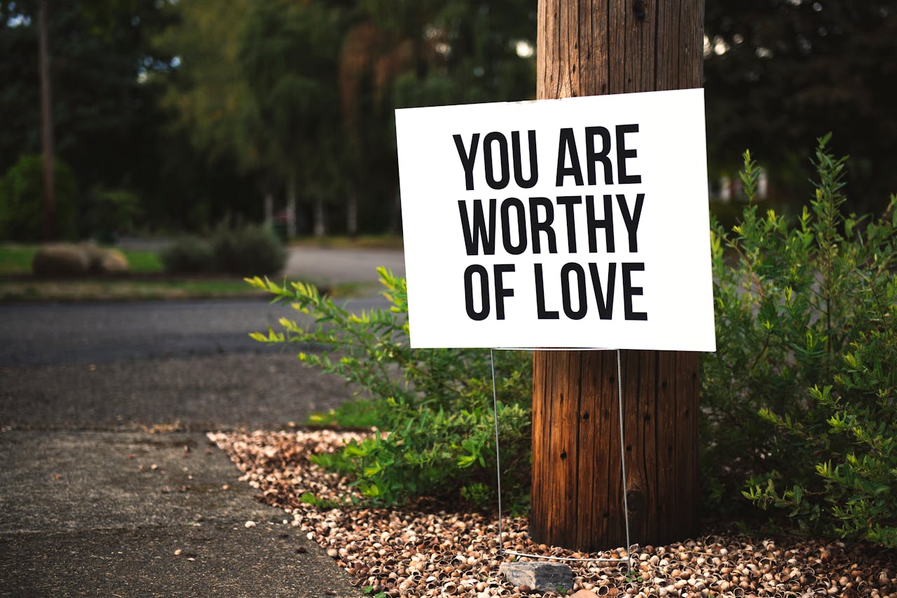 A positive message sign u0022You are worthy of loveu0022 in a park setting.